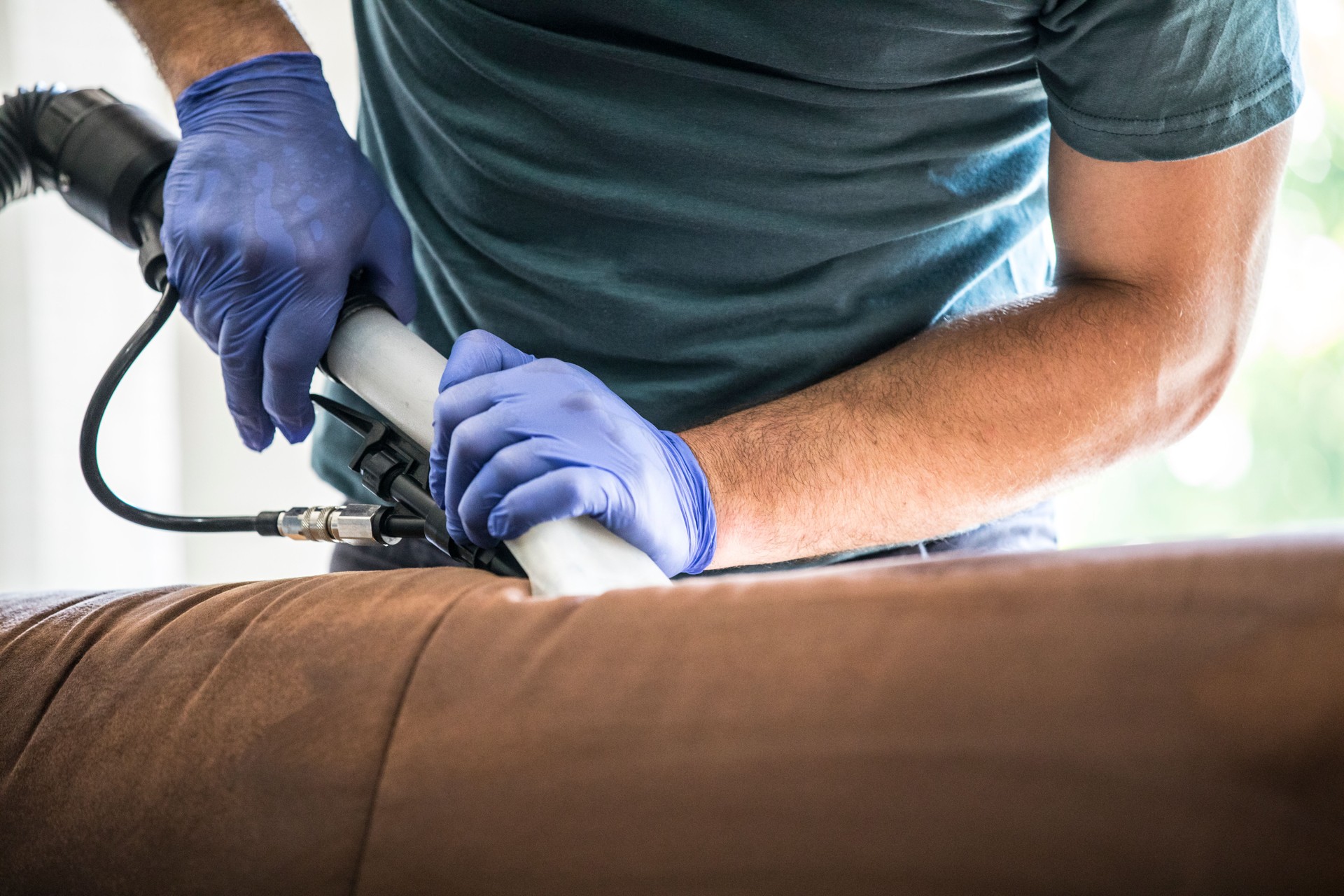 Man Using Wet Vacuum Cleaner To Clean Couch